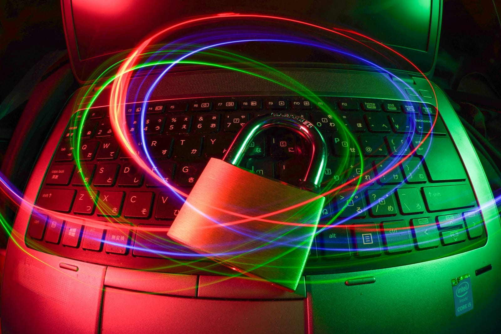 A fish-eye lens image of a laptop's keyboard with a large padlock on top with a swirling colourful light detail above it